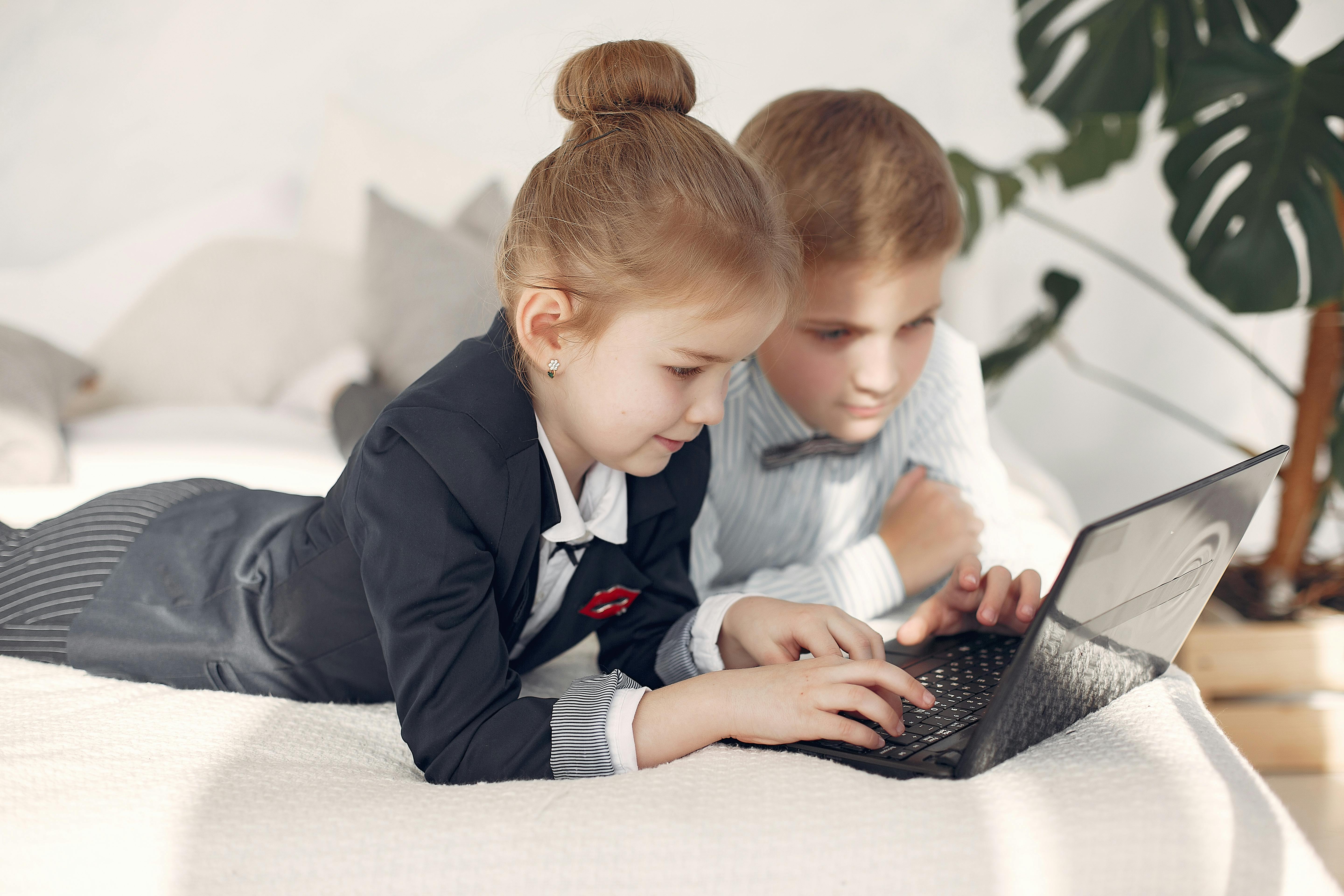 Two students in school uniform using a laptop together in the classroom